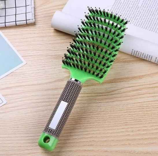 Cepillo para el cabello de cerdas mixtas y mango ergonómico color verde sobre fondo de madera