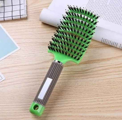 Cepillo para el cabello de cerdas mixtas y mango ergonómico color verde sobre fondo de madera